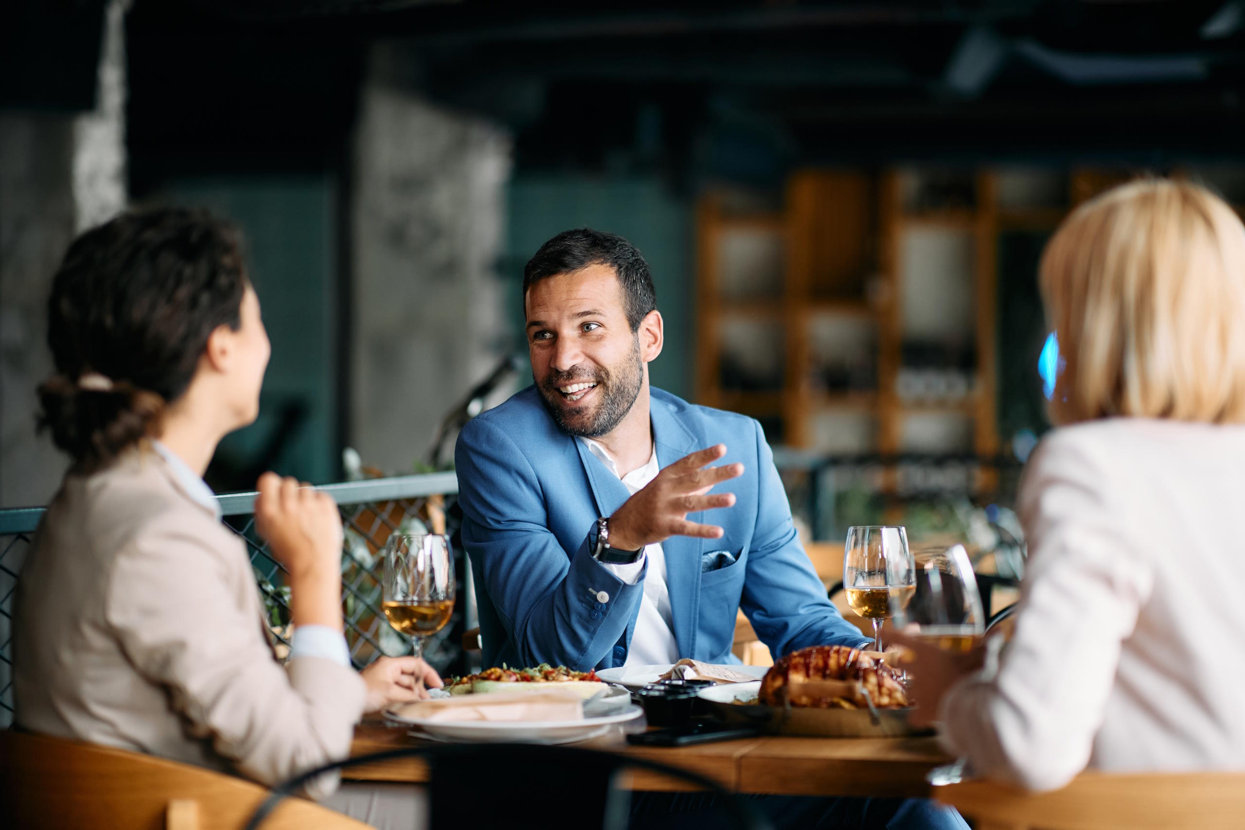 3 Personen sitzen in einem Restaurant an einem Tisch und unterhalten sich