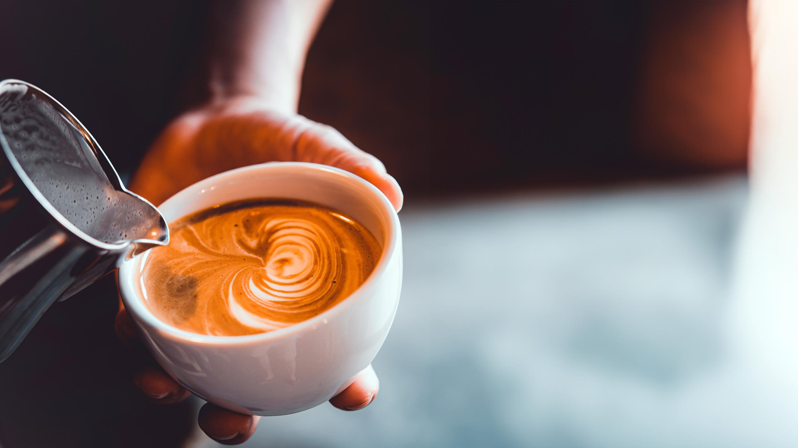 Barista verziert eine Tasse Kaffee mit Milchschaum